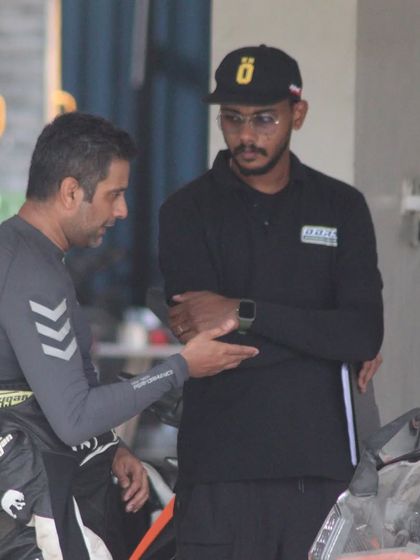 A candid moment between an instructor and a rider discussing track performance. These conversations are where real learning happens.