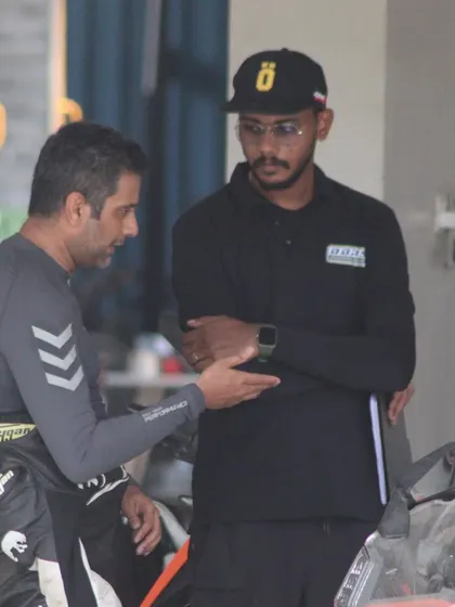 A candid moment between an instructor and a rider discussing track performance. These conversations are where real learning happens.