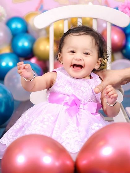Giggles and balloons make for the perfect first birthday photo. This happy baby is surrounded by colorful balloons, and our photographer captured her infectious laughter in this beautiful, candid shot.