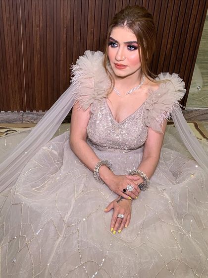 A close-up of the beige ball gown's bodice and feathered shoulders. The intricate embellishments and soft textures create a look of pure luxury.