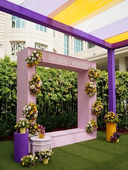 A fun and interactive photo booth for a Mehendi ceremony. The large pink frame, set against a lush green backdrop, is perfect for capturing sun-kissed memories.