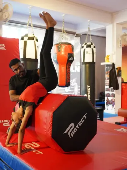 Our coach provides hands on support as a student practices a front walkover on a vaulting block. We prioritize safety and proper technique, ensuring every child masters skills at their own pace.