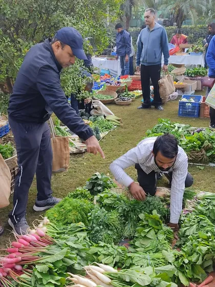 A customer getting help from a farmer to select the best greens.