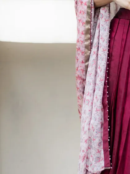 A detail of the Brick Maroon Mangalagiri silk lehenga, showing the pleated skirt and the delicately printed georgette dupatta with pearl edging.