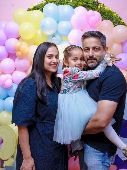 A family poses in front of a "My Little Pony" themed backdrop, featuring Rainbow Dash and Pinkie Pie. We can create parties based on a wide variety of magical characters.