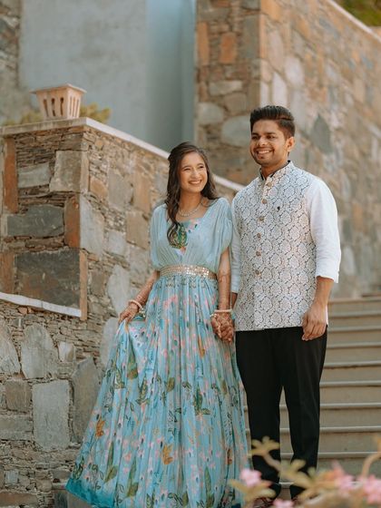 A relaxed and happy portrait of a couple holding hands on the steps of their wedding venue.