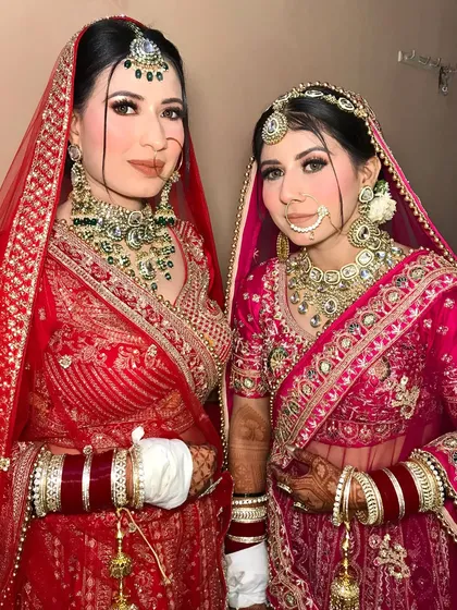 Two sister brides, one in red and one in magenta, both styled to perfection with complementary heavy bridal jewelry.