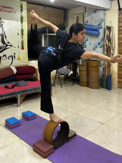 Balance is not just physical, it is mental. Here, a student practices a variation of Natarajasana (Dancer's Pose) on a yoga wheel, a technique that challenges core strength and sharpens focus.