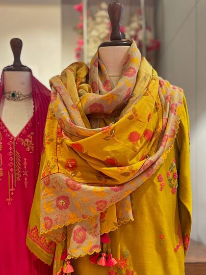 A close-up of a mustard yellow kurta with a printed floral dupatta, highlighting the tassels and intricate details.