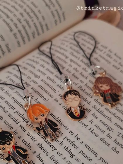 Another look at the magical Harry Potter phone charms, resting on an open book. They are the perfect accessory for any book lover and Potterhead.