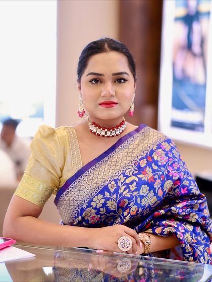 A direct-to-camera shot in my blue saree, showing the beautiful gold weaving and the red and white choker that complements the look.