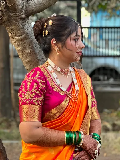 A side view highlighting the neat bridal bun and the intricate details of the pearl jewellery.
