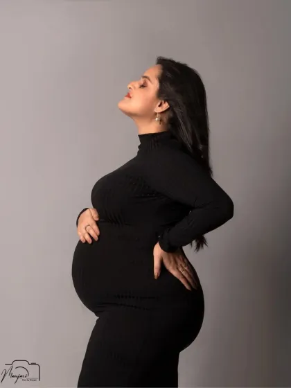A powerful and confident solo portrait, showcasing the beautiful silhouette of the baby bump in a sleek black bodycon dress.