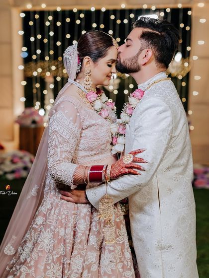 A tender forehead kiss, capturing the couple's emotions against a backdrop of soft fairy lights, a perfect end to their wedding day.