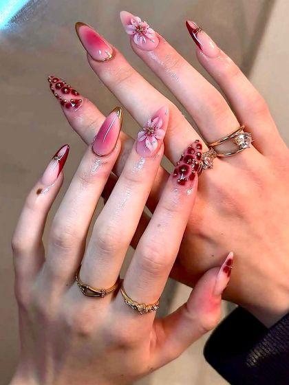 A bold and dramatic bridal look with sharp stiletto nails, featuring a deep red ombré, 3D florals, and intricate beadwork. This set is for the bride who wants to make a statement.