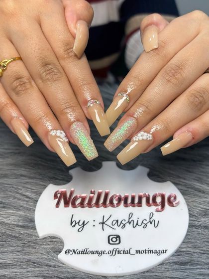 A sophisticated nude set on long square nails, featuring iridescent glitter and 3D floral accents.