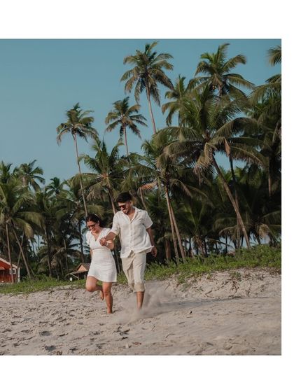 A fun, energetic shot of the couple running down a sand dune, with a line of palm trees in the background. It's full of life and joy.