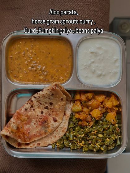 A comforting and nutritious meal of aloo paratha, horse gram sprouts curry, curd, and a duo of pumpkin and beans palya.