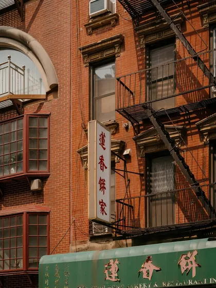 Architectural details and signage in Chinatown, NYC. The layers of fire escapes, windows, and signs tell a story of the neighborhood's history and density.