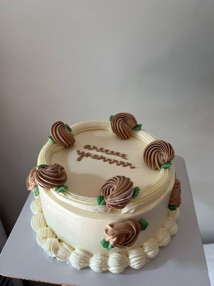 A chocolate mousse cake with a simple but elegant design. The top is decorated with piped chocolate roses and a sweet message.
