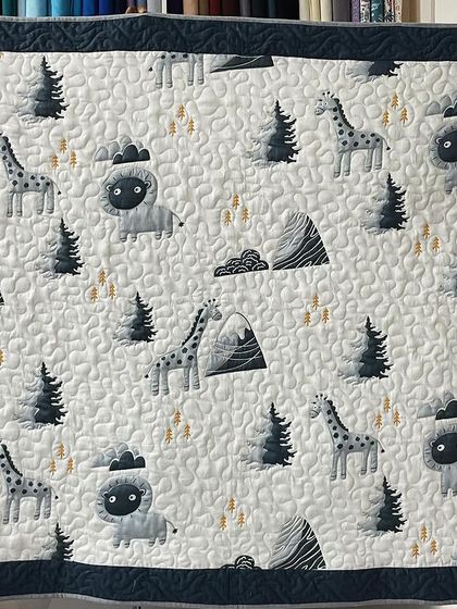 A sweet baby quilt with a woodland animal theme, featuring giraffes and lions.