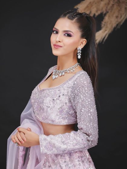 A half-length studio portrait of a model in a delicate lavender lehenga, showing off the detailed blouse and diamond jewelry.