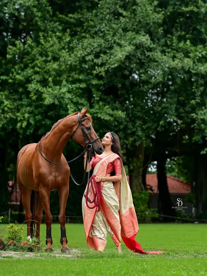A wide shot showing the connection between the model and the horse. This image tells a story of grace and strength, set against a lush green field.