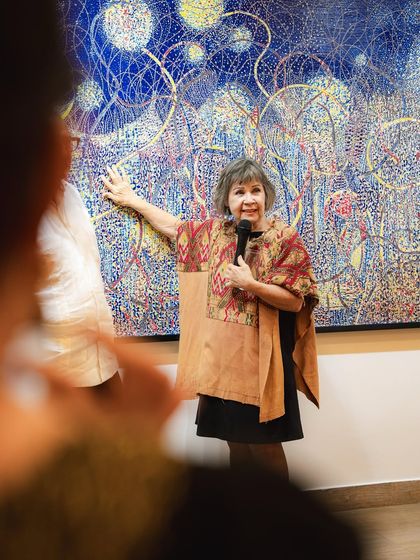 A photo from the opening of 'Call to the Mystic,' with artist Eva Malhotra guiding visitors through her work.