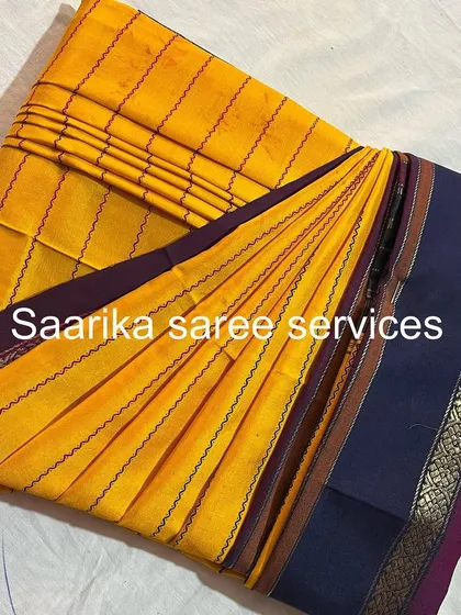 A traditional yellow Ilkal saree with a purple border, folded with care.