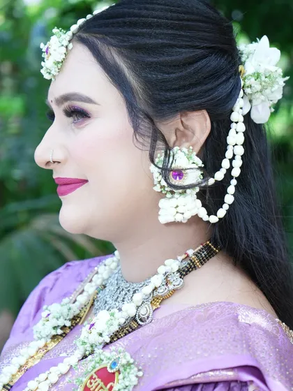 A side profile highlighting the floral hair accessories and earrings. The white orchids add a touch of modern elegance to the traditional design.