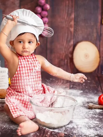 This little chef means business! With a whisk in hand, she's ready to whip up something delicious. I love capturing their determined and curious expressions as they interact with the props.