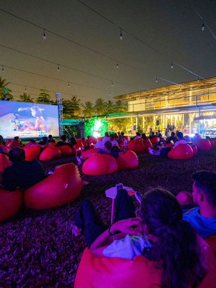 A wide shot of our outdoor cinema setup. The combination of the huge screen, comfy seating, and beautiful lighting makes for a magical night.