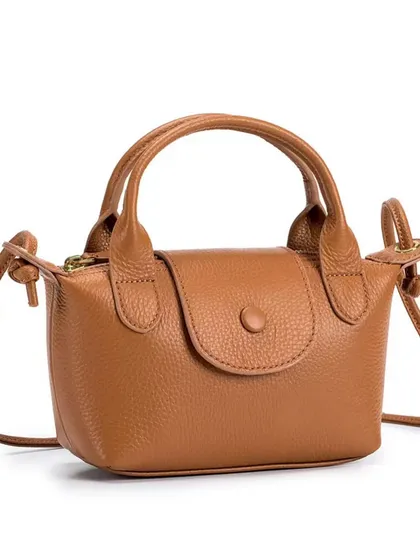 A studio shot of the Metro Mini in a classic brown colour. The image highlights the button-clasp flap and the soft, pebbled leather texture.