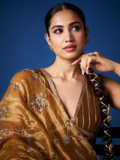 A stunning close-up of a model in the golden tissue saree, showcasing her flawless makeup and the saree's intricate details.