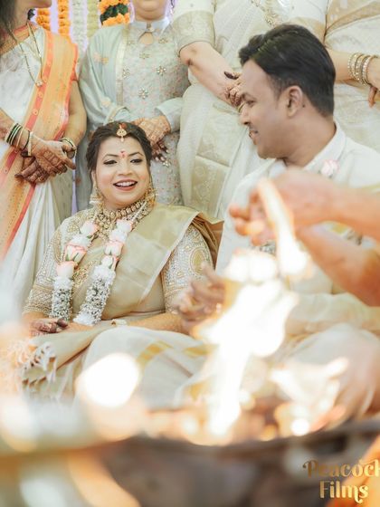 A candid shot of the couple sharing a smile during their wedding ceremony, with the sacred fire in the foreground.