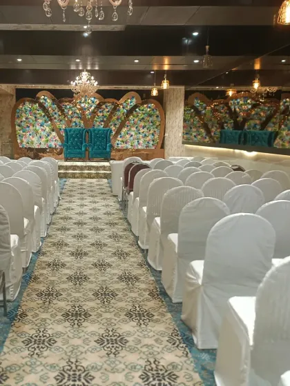 The Emerald Door banquet in Sanpada, set up for a function. The hall features white chair covers and a unique floral stage, all available under our limited 50k offer.