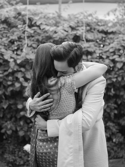 An emotional black and white shot of the bride and groom in a tight embrace after their first look, a moment of pure connection.