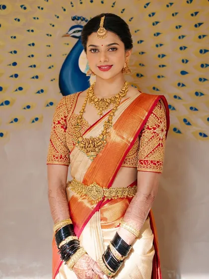 Another beautiful shot of Supritha, showing her complete bridal look against a peacock-themed backdrop, highlighting the classic red and white combination.