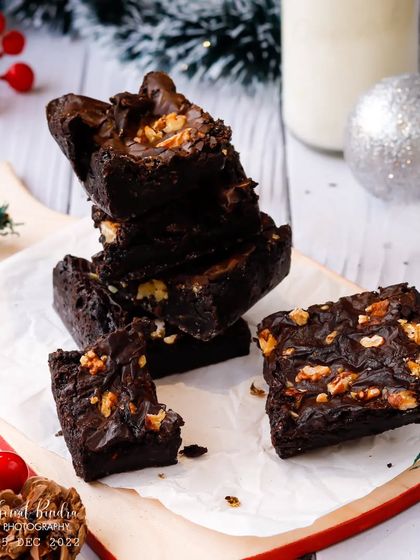 Feeling downie? Have a brownie. This bright and festive shot features a stack of walnut brownies on a cutting board, surrounded by Christmas decorations for a cheerful holiday treat.