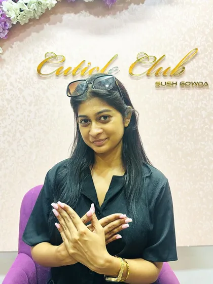 A happy client posing with her new nails in front of the Cuticle Club studio wall.