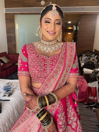 A happy bride in a beautiful pink lehenga, her hair styled in a classic updo.