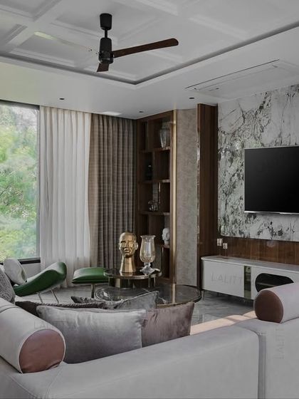 This lounge in our Chennai project offers a deliberate break from the noise. The space is structured yet soft, with a large sectional sofa, a marble feature wall for the TV, and large windows that connect the room to the lush greenery outside.