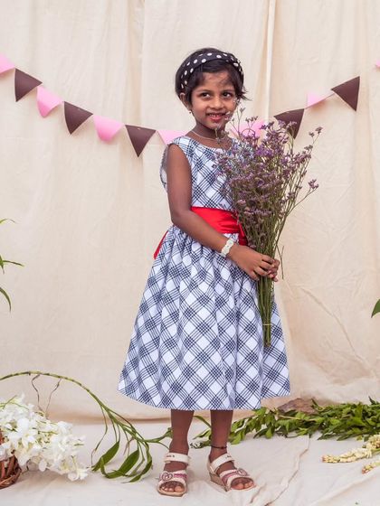 A classic black and white checkered dress gets a pop of color from a bright red sash. It's a versatile piece that can be dressed up or down for any occasion.