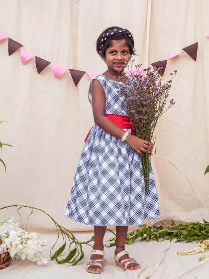 A classic black and white checkered dress gets a pop of color from a bright red sash. It's a versatile piece that can be dressed up or down for any occasion.