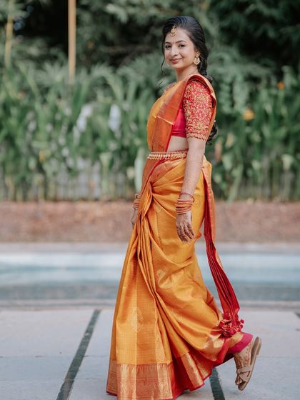 A side profile, showing the flow of the saree and the intricate hairstyle.
