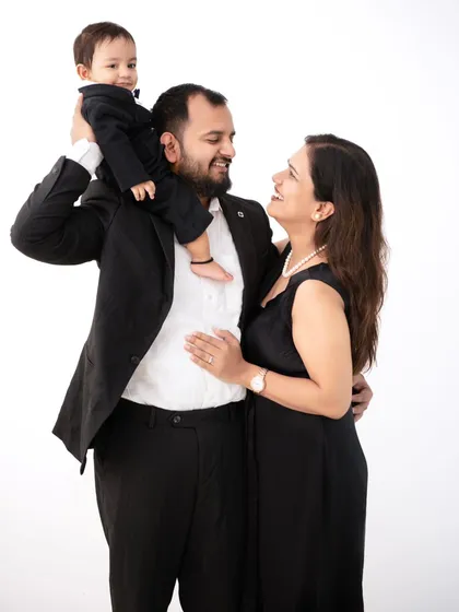 A playful and loving family portrait. The son, dressed in a tiny suit, gets a lift from his grandmother, showcasing the joy of an extended family photoshoot.