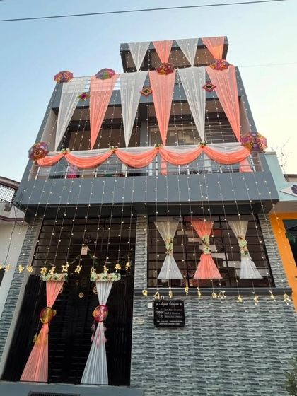 A modern house decorated with peach and white drapes and fairy lights. This design complements the architecture of the house while adding a festive wedding touch.