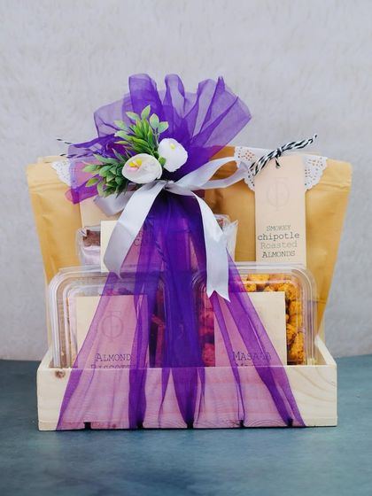 Add a touch of elegance with this wooden tray hamper. Wrapped in royal purple, it contains a mix of our sweet and savoury items like Almond Praline and Smoky Chipotle Almonds.