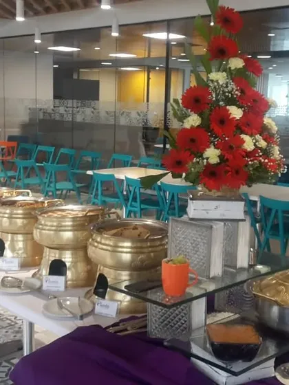An elegant buffet line ready for a corporate event. The long table is laden with a variety of dishes in our classic brass serving pots, complemented by a large floral centerpiece.