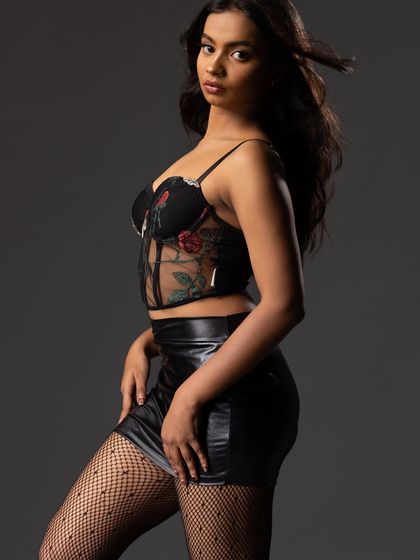 A side-profile shot of the model in the floral corset and leather skirt.